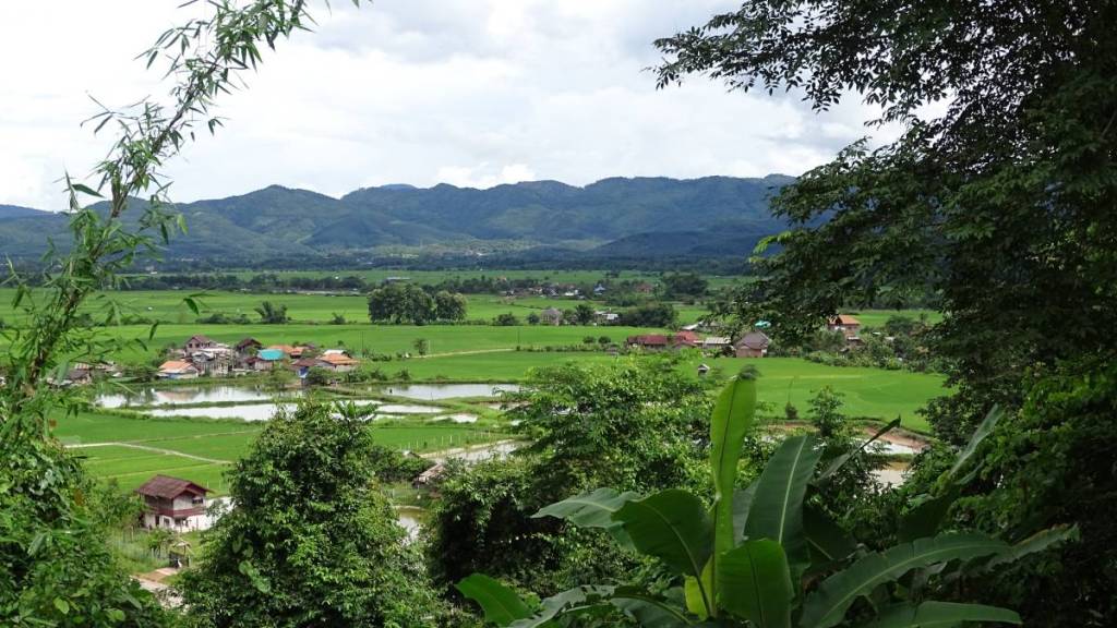 The bird eye view at the villages among paddy fields and mountains in the background