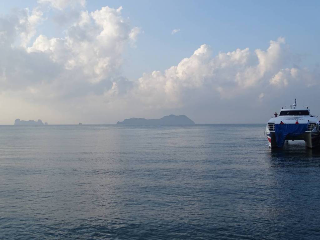 A catamaran to Ko Tao moored at the pier and small, rocky islands on the horizon