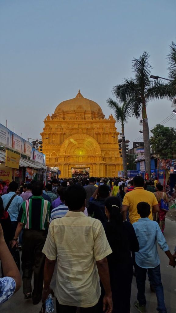 A large crowd heading to a huge, golden pandal shaped as a temple to celebrate Durga Puja 