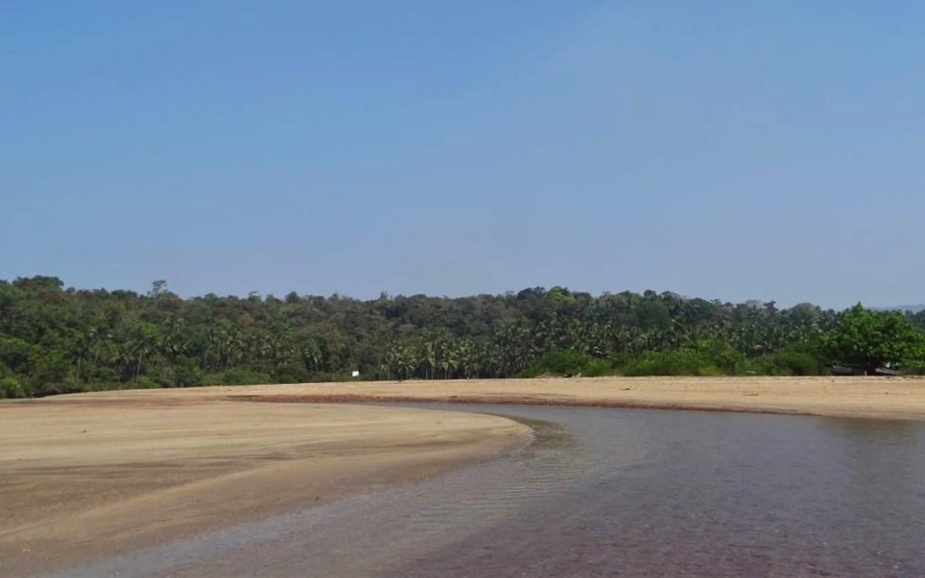 A small, very shallow river fed by estuary further in the background winds its way through sandy Agonda beach 